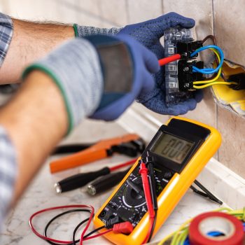 Electrician at work with screwdriver fixes the cable in the sockets of a residential electrical system. Construction industry.