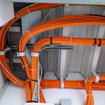 many orange network cables run bundled under the ceiling of a server room